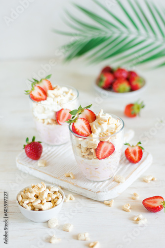 Desserts of cookies and whipped cream with strawberries in glasses, background and foreground in blur