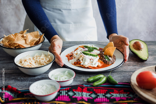 Mexican woman hands preparing chilaquiles with red sauce and eating traditional mexican food for breakfast in Mexico Latin America  hispanic people