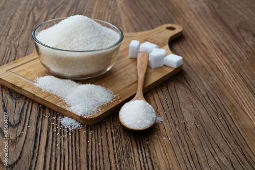A bowl granulated sugar and sugar cubes on the board
