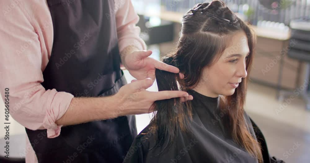 Caucasian male hairdresser holding female client's hair and advising her at salon, slow motion Caucasian male hairdresser holding female client's hair and advising her at salon, slow motion