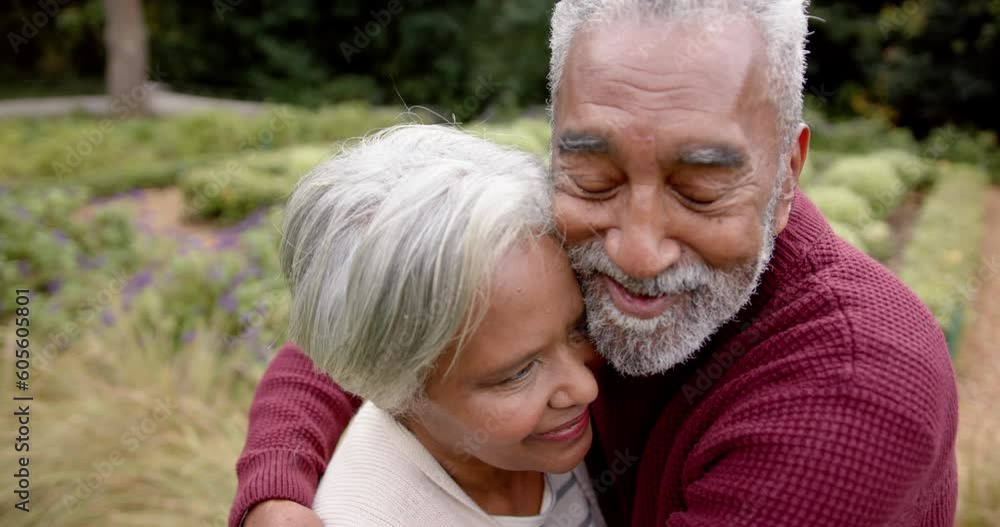 Happy senior biracial couple embracing and smiling in garden, unaltered, in slow motion Happy senior biracial couple embracing and smiling in garden, unaltered, in slow motion