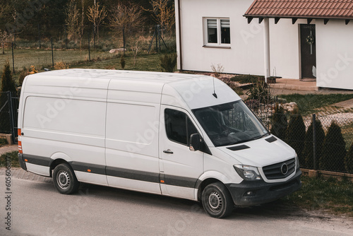 A white delivery van is parked on the side of the road. Door-to-door delivery mockup. Logistics concept. © AlexGo