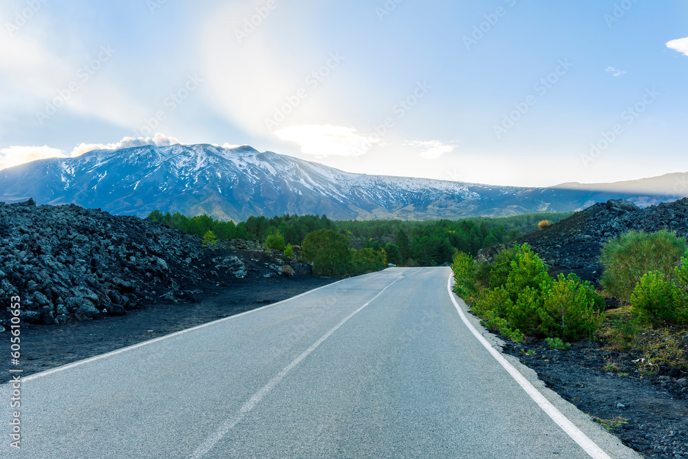 picturesque view of highland landscape of highway to mountain with old asphalt, blach sides with green forest and high snow mountain with amazin blue cloudy sky picturesque view of highland landscape of highway to mountain with old asphalt, blach sides with green forest and high snow mountain with amazin blue cloudy sky
