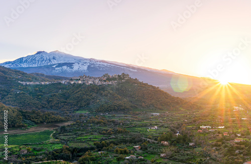 amazing mountain sunset landscape of green mountains and hills, old highland town and snow top mountain on backgroud