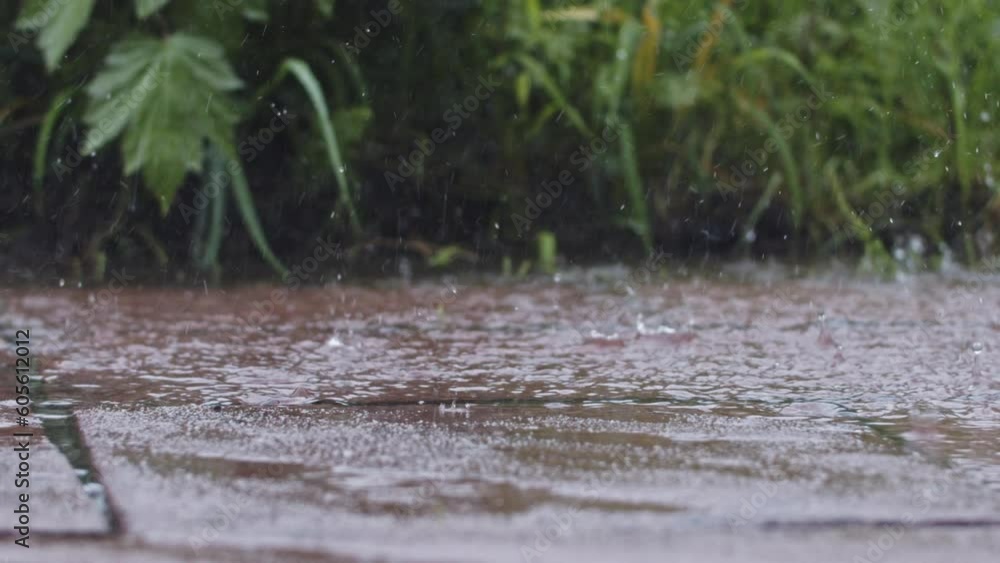 Handheld slow motion shot of rain and hail, grass in the background. Close up shot of a puddle of water. Hail hitting the water creating small splashes. Handheld slow motion shot of rain and hail, grass in the background. Close up shot of a puddle of water. Hail hitting the water creating small splashes.