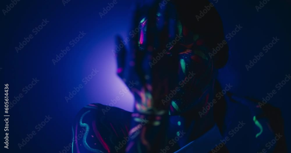 Young Dancer with Glowing Body Art Paint and White Clothes Creates Magic with Contemporary Dance Solo Routine. Choreographer Gestures Hands in a Modern Dance Show on a Dark Stage with a Single Light Young Dancer with Glowing Body Art Paint and White Clothes Creates Magic with Contemporary Dance Solo Routine. Choreographer Gestures Hands in a Modern Dance Show on a Dark Stage with a Single Light