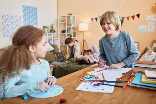 Portrait of brother and sister drawing together and laughing cheerfully