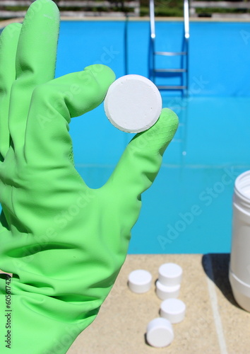 White mini chlorine tablet in the hand of a pool disinfection service worker. The beginning of the swimming season is a hot summer.