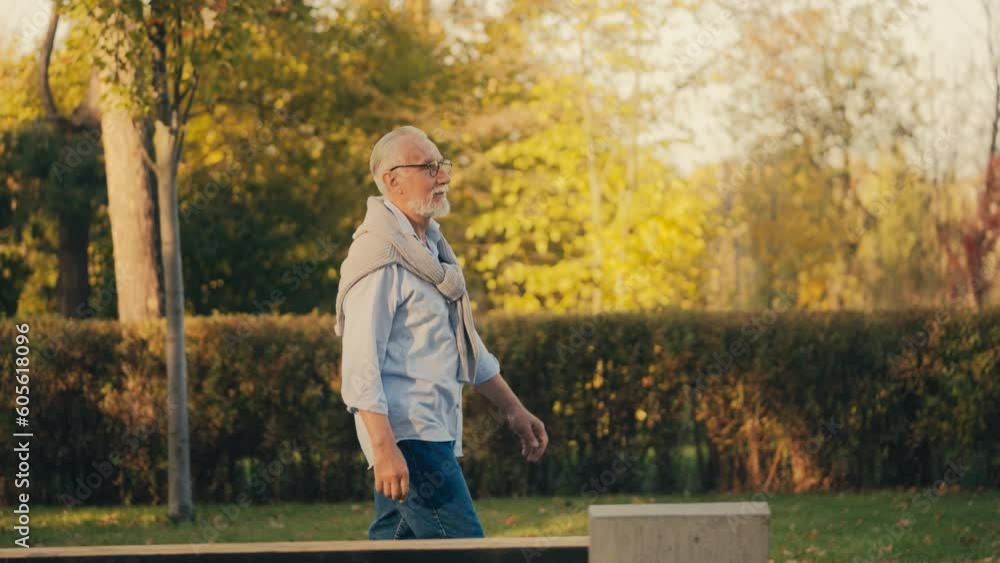 Pleased man in his 60s walking in urban park, enjoying autumn nature, relax time Pleased man in his 60s walking in urban park, enjoying autumn nature, relax time