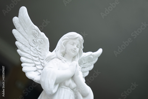 Cupid stucco doll, white girl, clasped hands, blurred light background