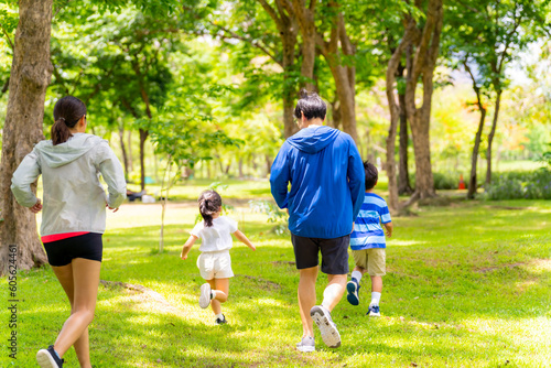 Happy Asian parent and little kids enjoy and fun outdoor lifestyle on summer vacation. Father, mother and child jogging workout exercise together at park. Family relationship and health care concept.