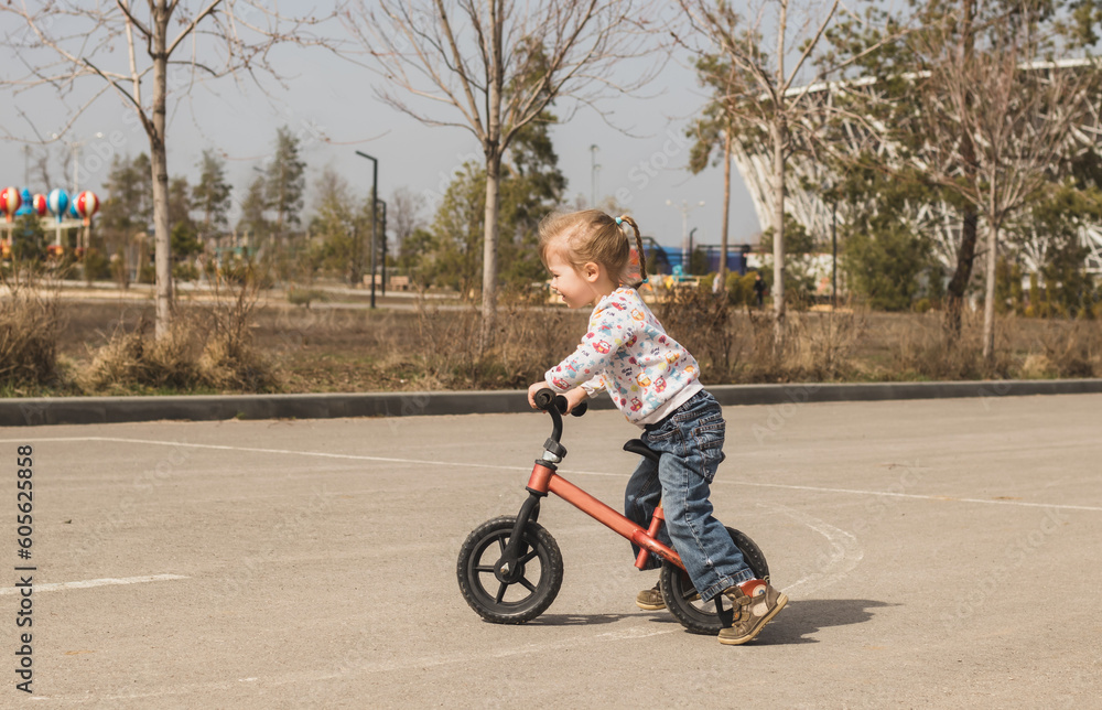 cheerful little child girl riding a bike in the city park in sunny day outdoors cheerful little child girl riding a bike in the city park in sunny day outdoors