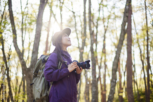 夏の森で趣味の撮影を楽しむ30代日本人女性のカメラマン