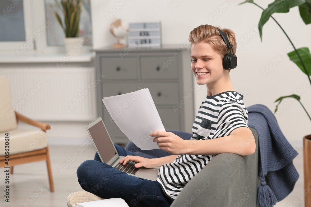 Online learning. Smiling teenage boy with laptop looking on essay at home Online learning. Smiling teenage boy with laptop looking on essay at home