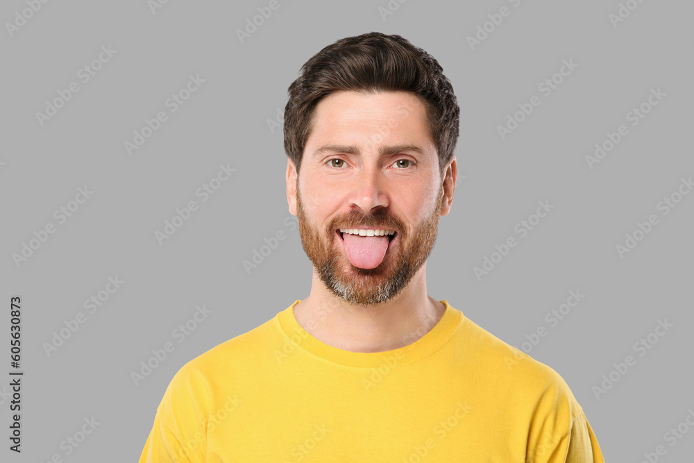 Obraz premium Man showing his tongue on gray background