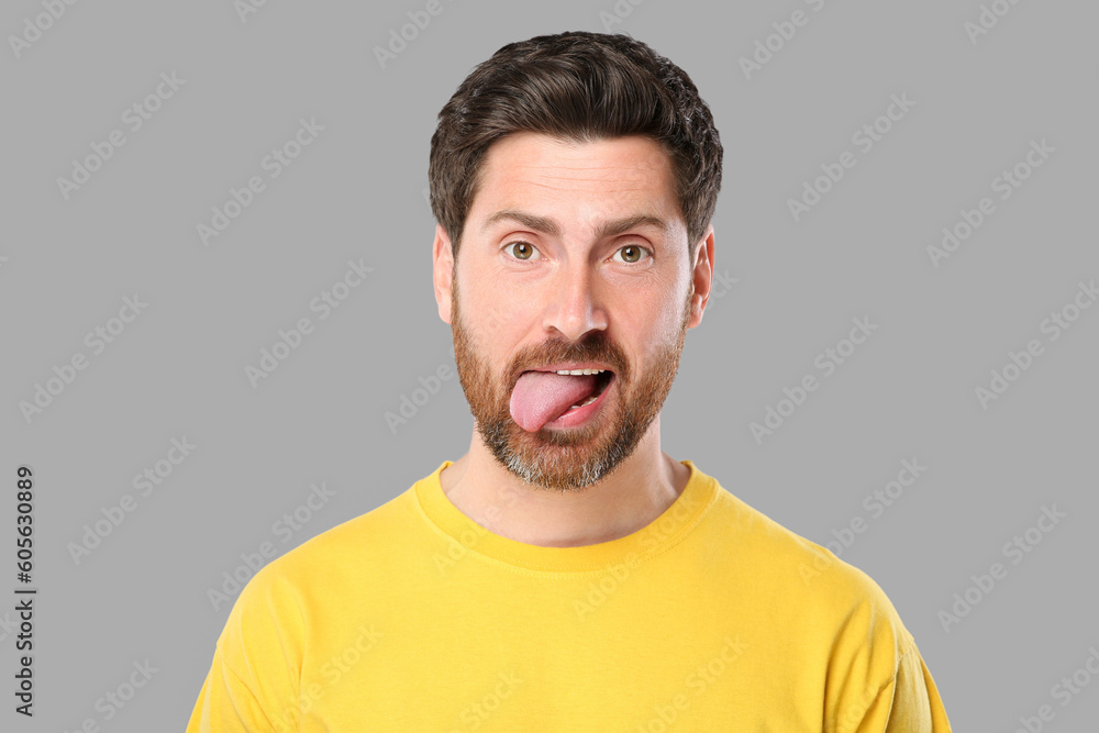 Man showing his tongue on gray background