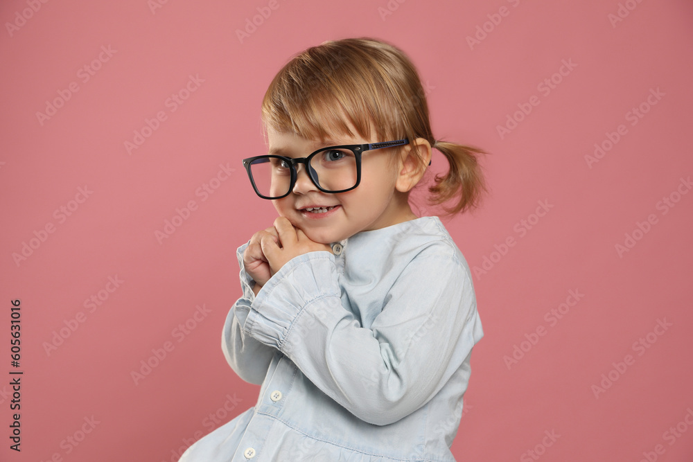 Cute little girl in glasses on pink background