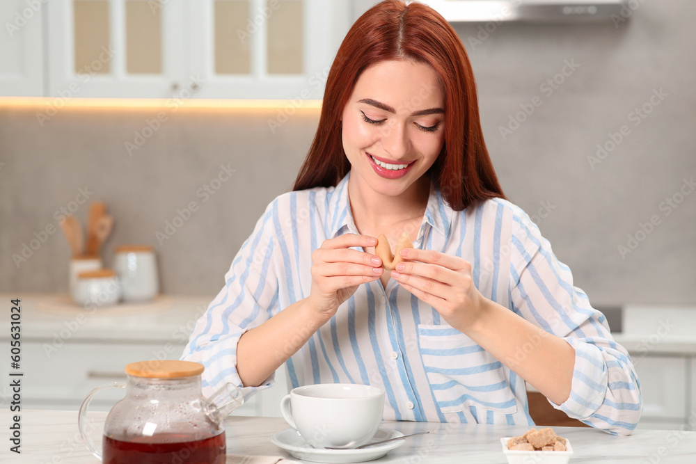 Happy woman with red dyed hair holding fortune cookie in kitchen Happy woman with red dyed hair holding fortune cookie in kitchen
