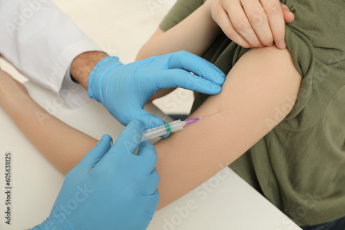 Doctor giving hepatitis vaccine to patient at table  closeup