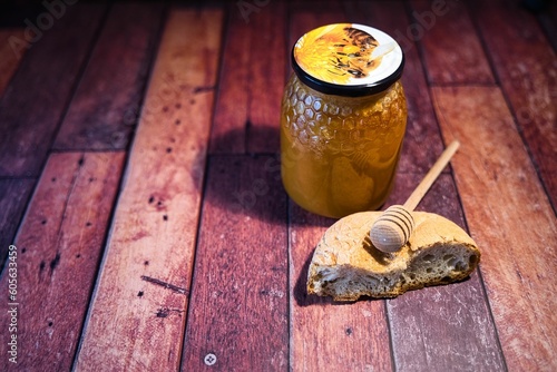 Closeup of a honey jar and bread in a wooden surface photo