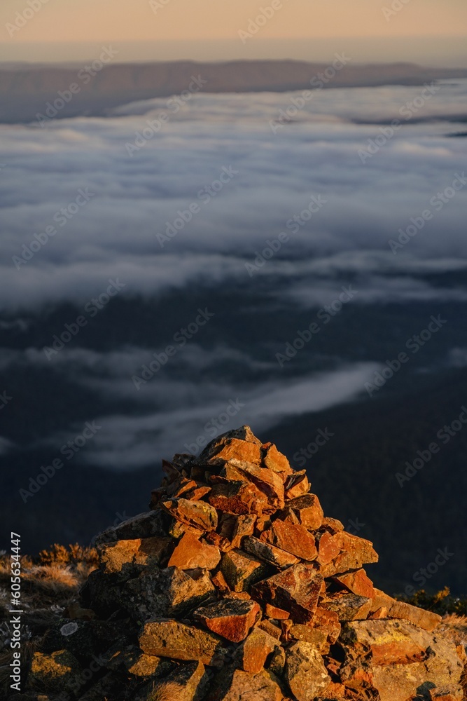 Pile of sunlit stones with clouds from above and orange skyline background