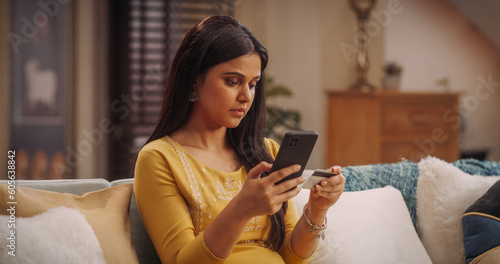 Gorgeous Indian Woman Using Smartphone and Credit Card: Effortlessly Navigating Online Shopping, Making Secure Transactions, and Enjoying the Convenience of E-commerce. Medium Shot