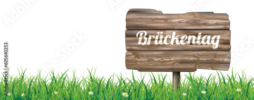 Ein Holzschild Brückentag auf der grünen Wiese