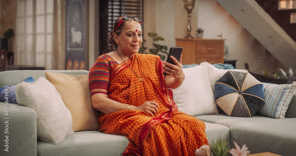 Obraz premium Elderly Woman Using Smartphone for Video Call: GreetingFriends, Sharing Joyful Moments, and Talking with Family Relatives. Embracing Technology to Stay Social and Active. Medium Shot.