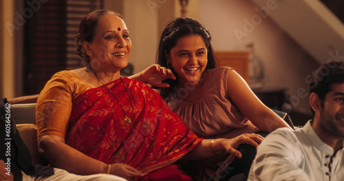Photography Portrait of Happy Indian Mother and Daughter Enjoying Movie Playing on TV at Home Together with Their Family