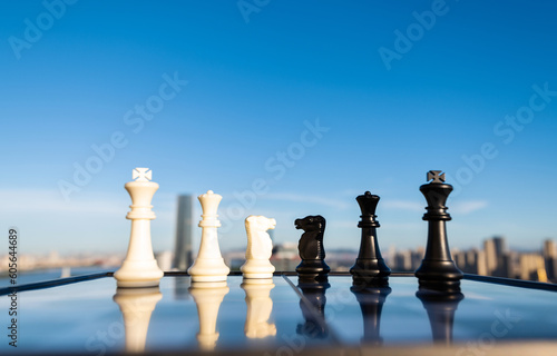 Black and white chess pieces on city background