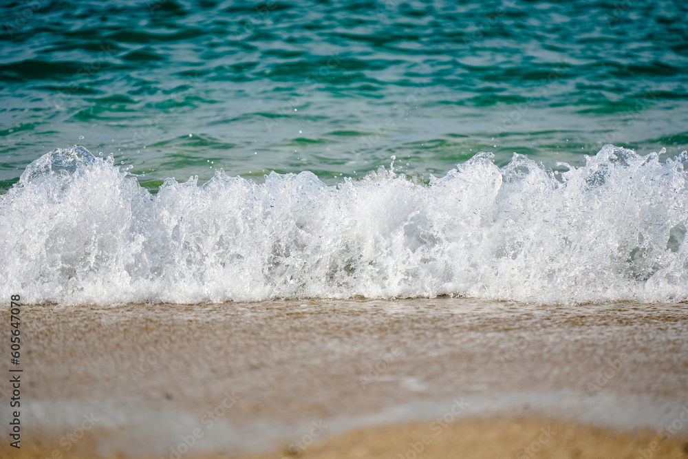 Closeup shot of the turquoise waves of the sea hitting the sandy beach