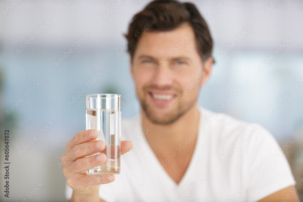man holds out a glass of water man holds out a glass of water