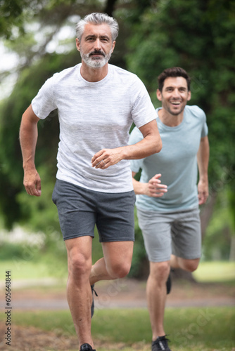 happy father and son jogging together outdoors in park