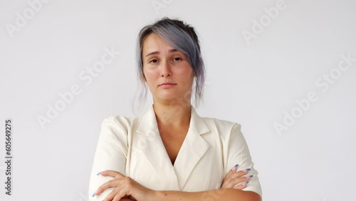 Eye from foot to head, woman raises her eyebrows and looks straight to camera, sitting with her arms folded across her chest. Portrait shot against white background photo