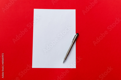 Blank paper and a pen on red background