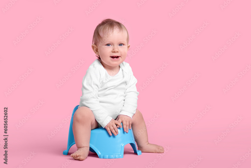 Little child sitting on baby potty against pink background Little child sitting on baby potty against pink background