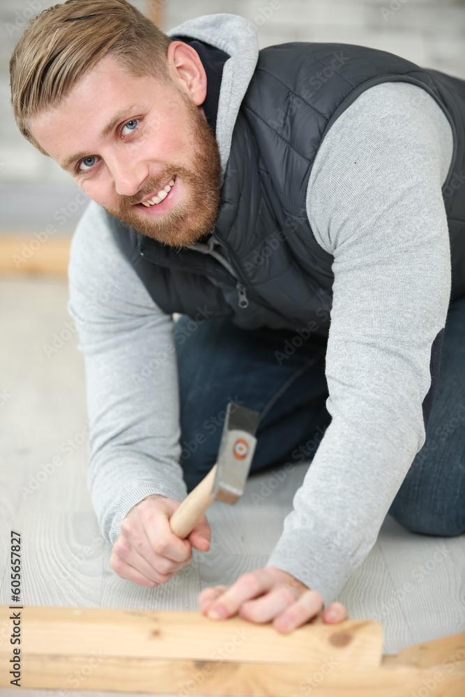 man hammering a nail in the floor
