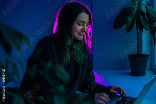 Girl typing message on a laptop, in the dark under blue light of the moon. Fingers running on keyboard. Freelance work. Computer. Night. Writing article, letter.Girl typing message on a laptop, in the