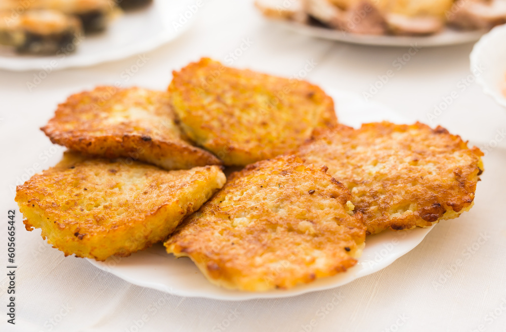 Fried grated potato pancakes with sour cream on white plate Fried grated potato pancakes with sour cream on white plate