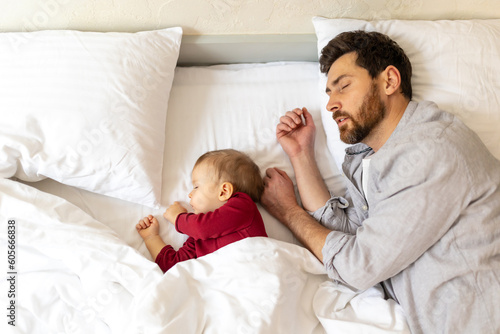 Father and little baby sleeping together in bed.