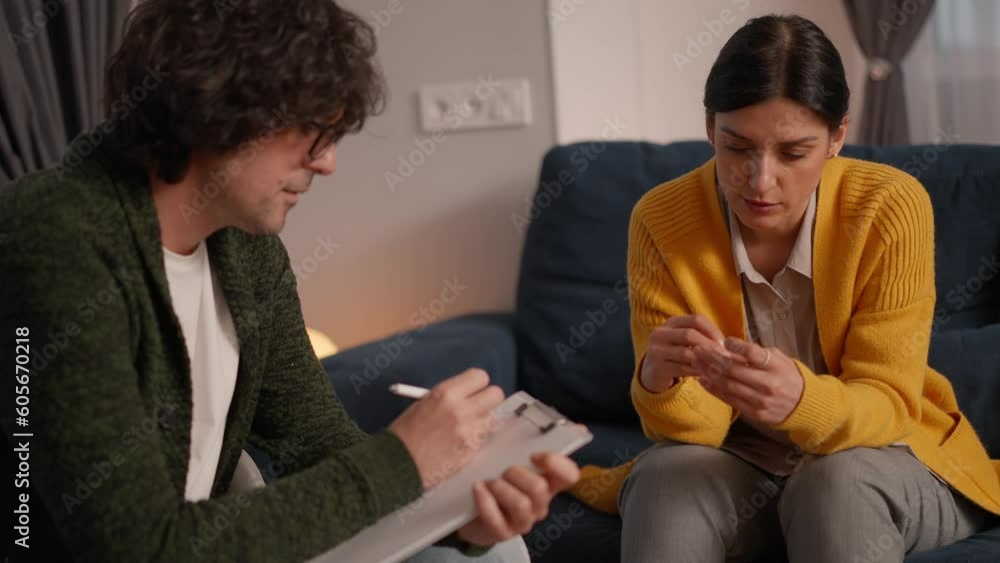 Depressed woman having a therapy session, she is talking and the therapist is writing notes, mental disorders and psychology concept Depressed woman having a therapy session, she is talking and the therapist is writing notes, mental disorders and psychology concept