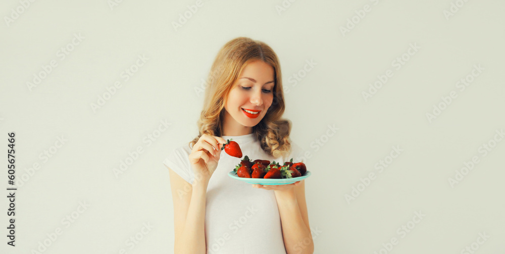 Portrait of happy smiling woman holding plate with fresh strawberries on white background Portrait of happy smiling woman holding plate with fresh strawberries on white background