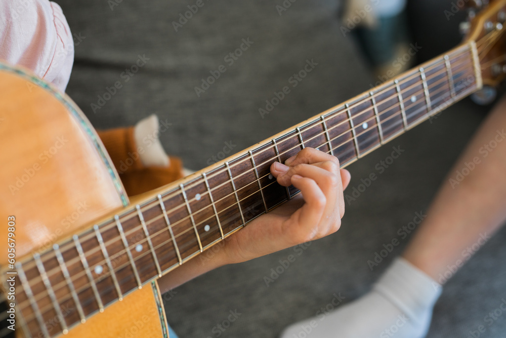Obraz premium Child girl hand playing guitar in room - leisure music and hobby concept