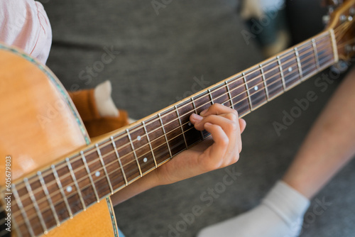 Child girl hand playing guitar in room - leisure music and hobby concept