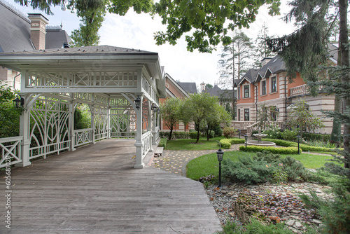 view of a white wooden gazebo with a large house with a garden