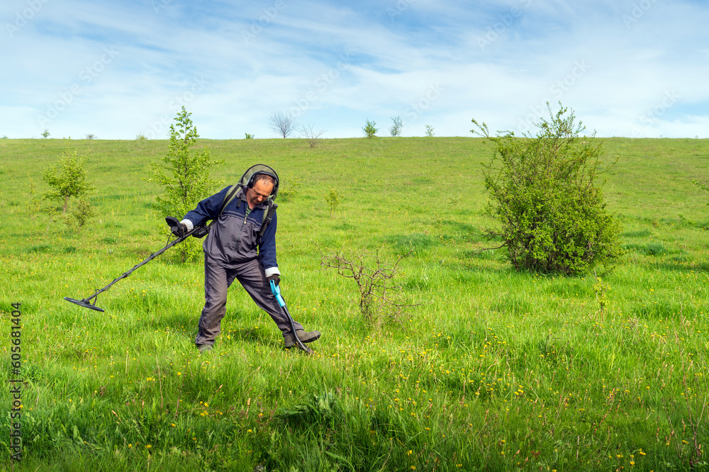 A man with a metal detector. Treasure hunter with metal detector and lipata. Man digs for treasure on the lawn A man with a metal detector. Treasure hunter with metal detector and lipata. Man digs for treasure on the lawn