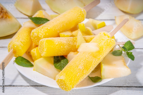 

 Melon ice cream popsicle, sweet sorbet lollypops, homemade gelato on sticks, with slices of fresh cantalupa melon and mint leaves 