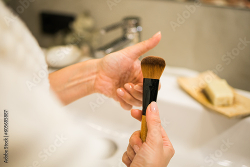 Female hand holds makeup brush in bathroom. Make-up artist profession concept. Variety of visagist tools glamor accessory