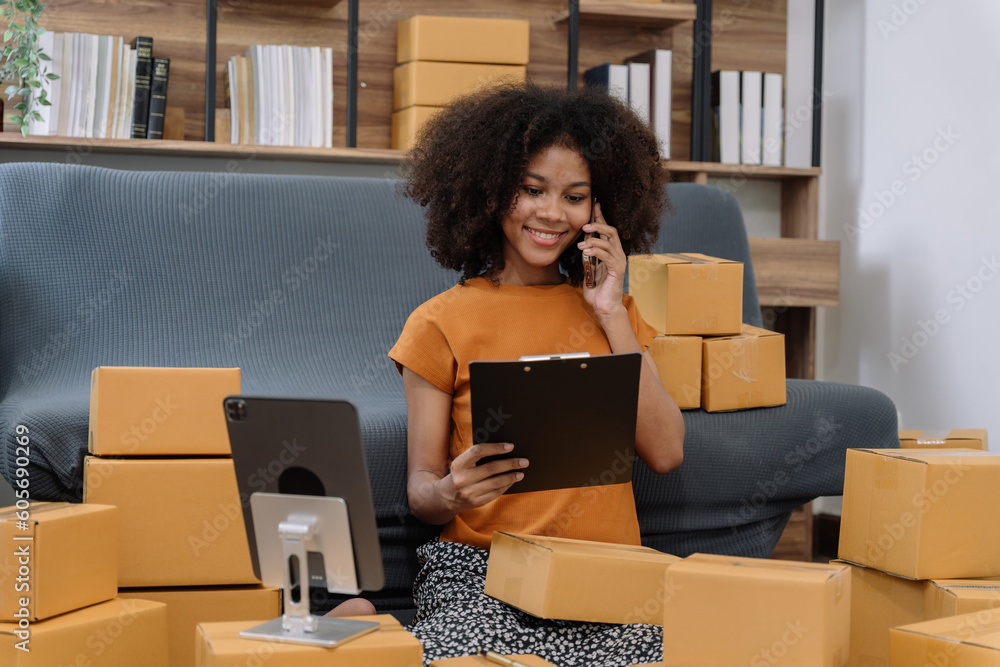Startup or small business entrepreneur in e commerce, or logistics in remote startup at home. African American female owner selling online on the Internet, SME, shipping boxes, store success. Startup or small business entrepreneur in e commerce, or logistics in remote startup at home. African American female owner selling online on the Internet, SME, shipping boxes, store success.