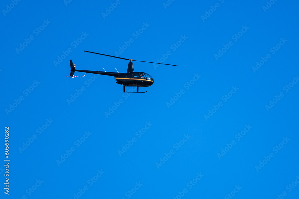 Black helicopter flying in clear blue sky Black helicopter flying in clear blue sky